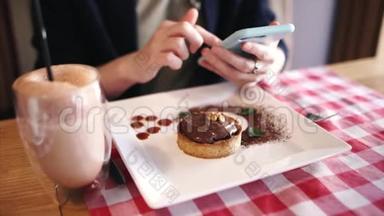 小女孩用智能手机，选择食物的<strong>照片</strong>，坐在咖啡馆里吃着甜点在网上<strong>翻</strong>来<strong>翻</strong>去。